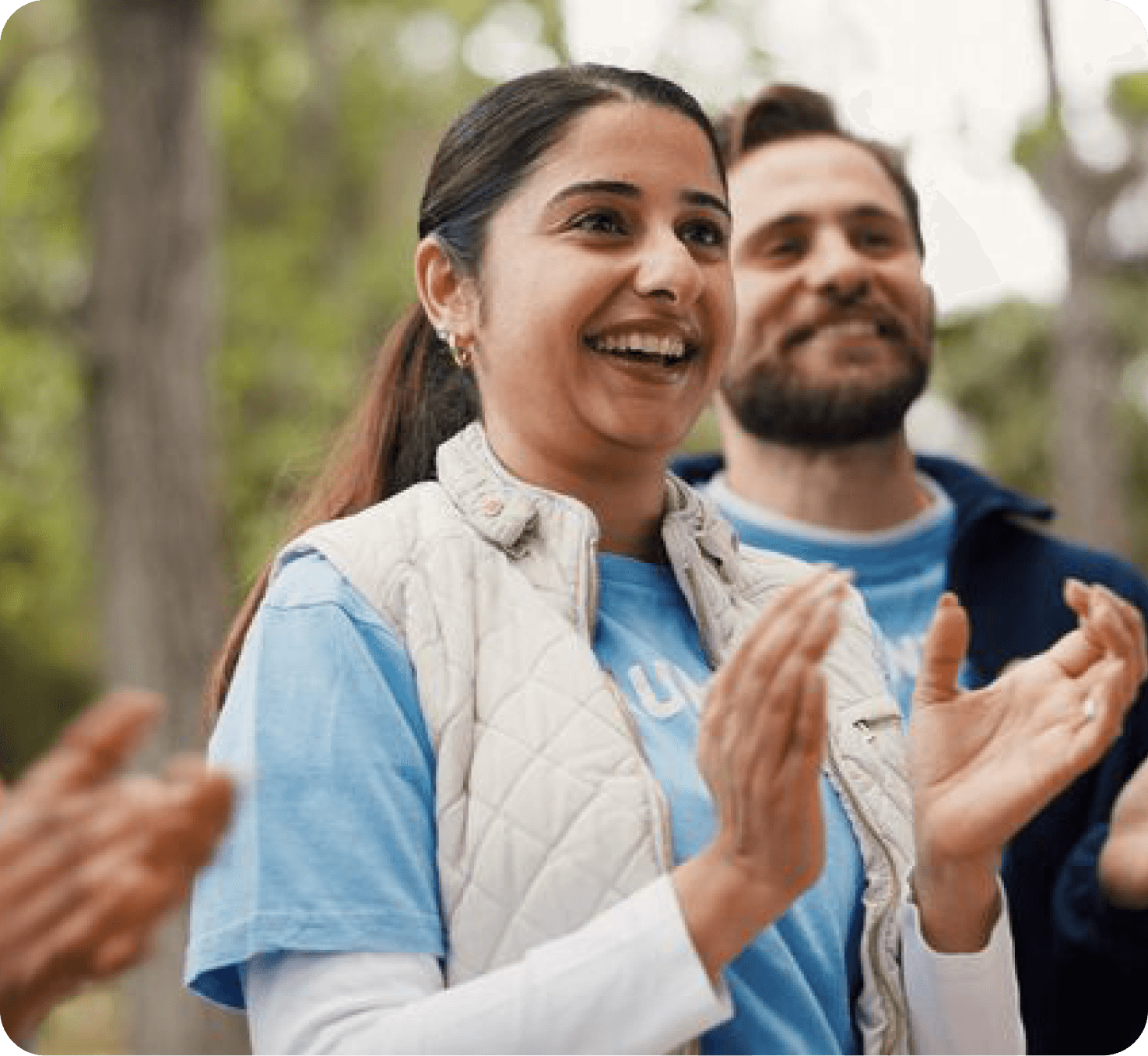 Volunteers smiling and clapping outdoors