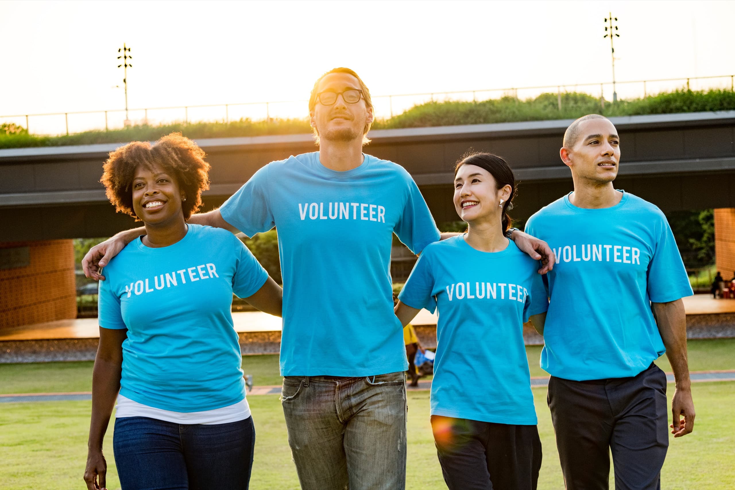Four volunteers in blue shirts smiling together